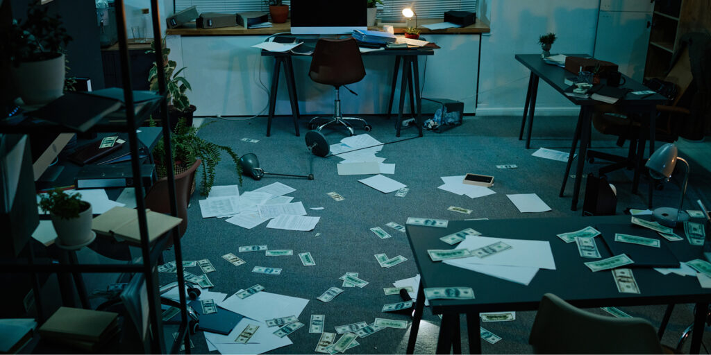 Dağılmış evraklar ve yere saçılmış paralarla karışık, dağınık bir ofis ortamı
